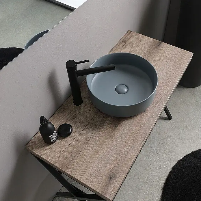 Kiamami Valentina Badmöbel-Set - Schwarz - Rundes graublaues Keramik-Aufsatzwaschbecken mit matt-schwarzem Wasserhahn auf einer rustikalen Holzablage im Bad.
