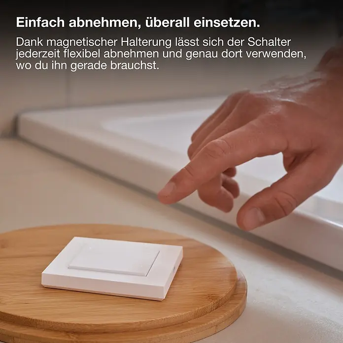 Osram Smart+ Schalter 4G matter - Weiß, Innen - Hand berührt einen weißen tragbaren Smart-Schalter auf einer Bambusbasis.