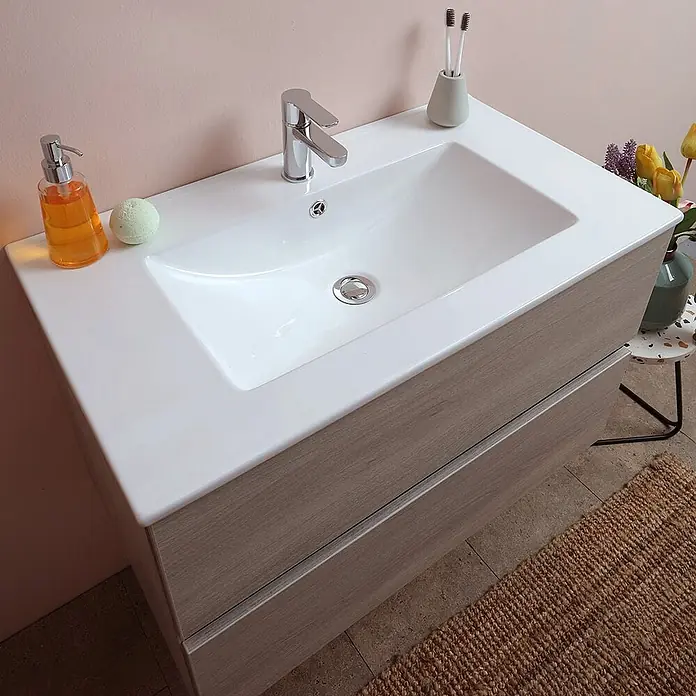 Kiamami Valentina Badmöbel-Set - Helles Holz - Moderner Badunterschrank mit weißem integrierten Waschbecken und zwei hellen Holzschubladen, im Badezimmerambiente.