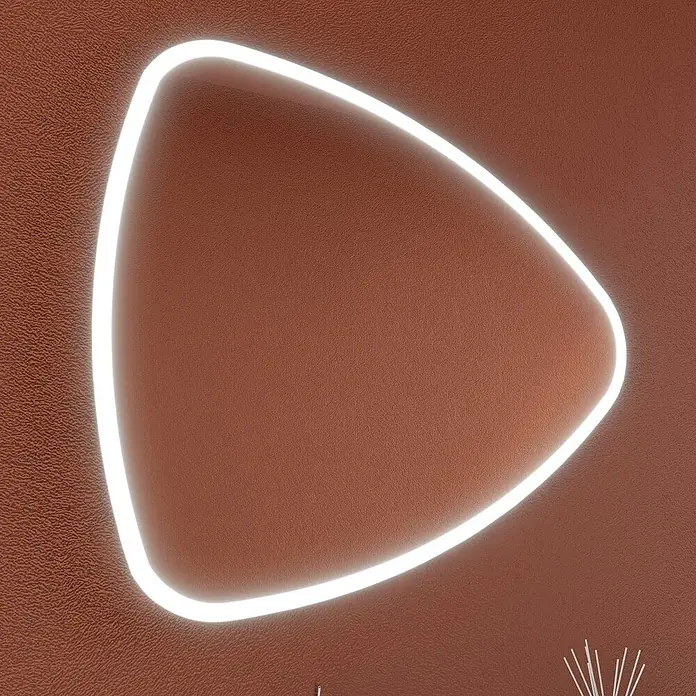 Kiamami Valentina Badmöbel-Set - Grau - Weiß leuchtendes LED-Licht in abgerundeter Dreiecksform auf einer strukturierten rotbraunen Wand.