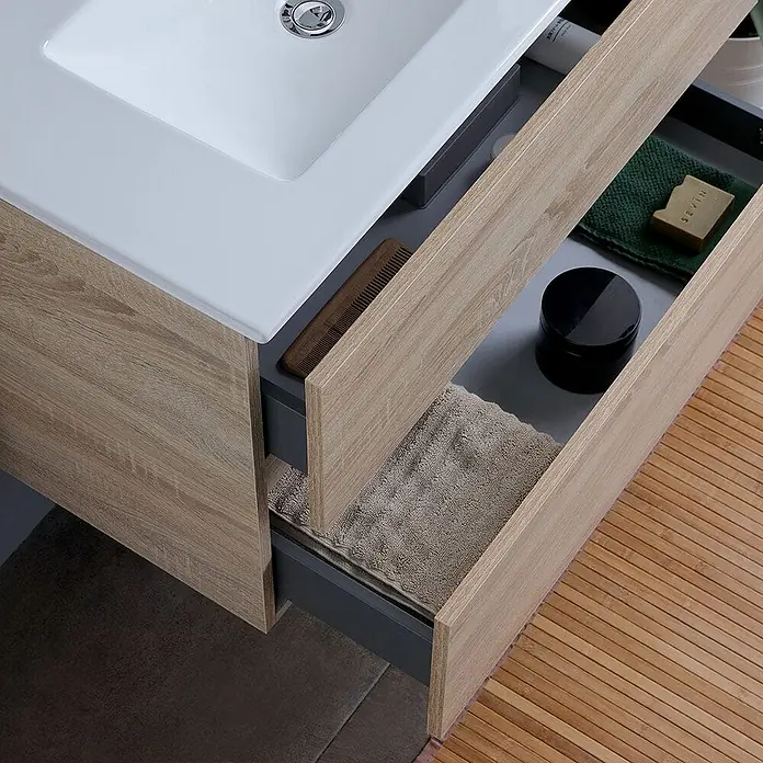 Kiamami Valentina Badmöbel-Set - Braun - Badezimmerschrank mit weißem Waschbecken und zwei hellen Holzschubladen, teilweise geöffnet für Stauraum.