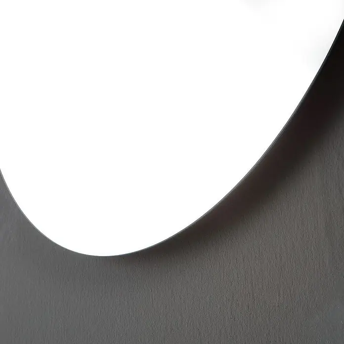 Kiamami Valentina Badmöbel-Set - Weiß - Gekrümmte weiße Leuchte wirft sanften Schein und Schatten auf eine graue Wand.