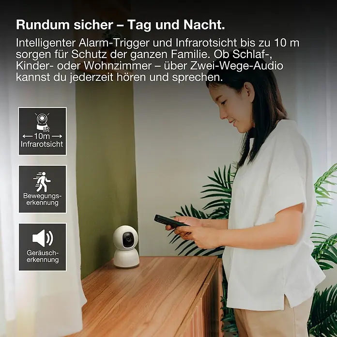 Osram Smart+ Überwachungskamera 360 - Weiß - Eine weiße Überwachungskamera auf einer Holzfläche, daneben eine Frau, die sie per Smartphone steuert.