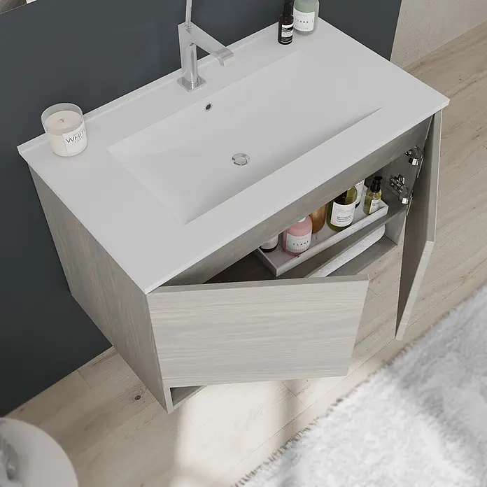 Kiamami Valentina Badmöbel-Set - Helles Holz - Heller grau gebeizter Waschtischunterschrank mit weißer Arbeitsplatte und integriertem Waschbecken, offene Türen zeigen Pflegeprodukte.
