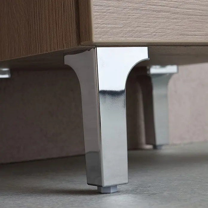 Kiamami Valentina Badmöbel-Set - Holz mittel - Glänzende Chrommöbelfüße tragen einen hellen Holzschrank. Die Füße sind mit Bodengleitern ausgestattet.