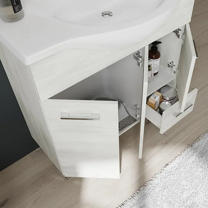 Kiamami Valentina Badmöbel-Set - Weiß - Heller Holzmaserung-Badezimmerunterschrank mit weißem Waschbecken, offenen Türen und teilweise geöffneter Schublade mit Toilettenartikeln.