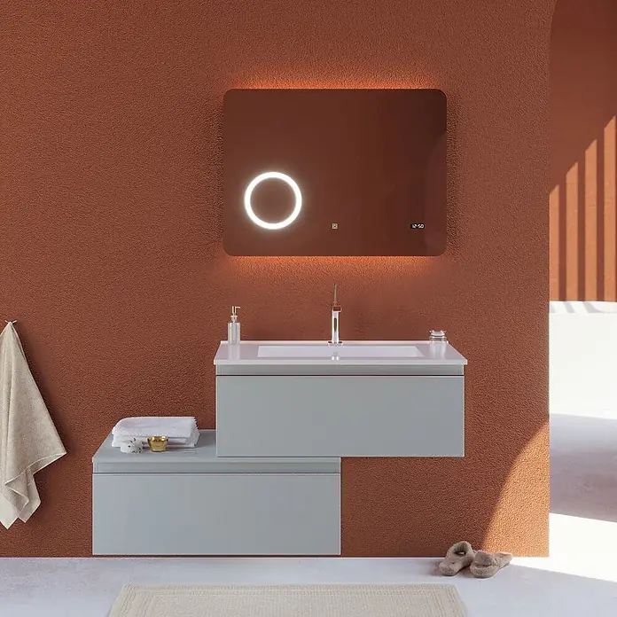 Kiamami Valentina Badmöbel-Set - Grau - Moderne hellgraue Badmöbel mit Waschbecken und smartem LED-Spiegel an Terrakottawand.
