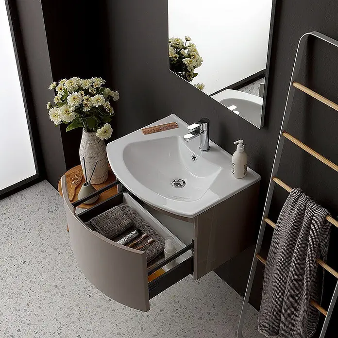 Kiamami Valentina Badmöbel-Set - Beige - Eck-Badezimmerschrank mit weißem Waschbecken und offener geschwungener taupefarbener Schublade.