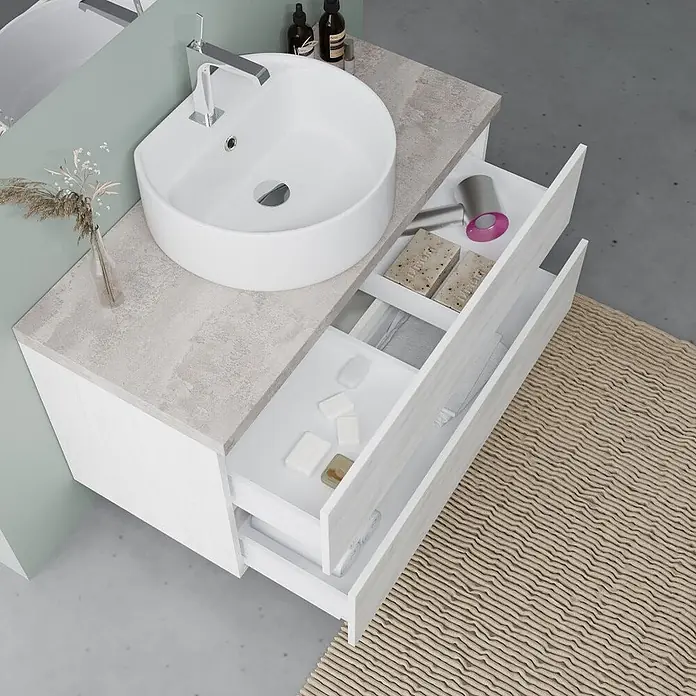 Kiamami Valentina Badmöbel-Set - Weiß - Weißer Badschrank mit hellgrauer Arbeitsplatte und weißem Waschbecken. Offene Schubladen zeigen organisierten Stauraum für Toilettenartikel.