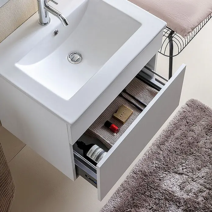 Kiamami Valentina Badmöbel-Set - Weiß - Weißer Badunterschrank mit integriertem Waschbecken und offener Schublade, die Pflegeprodukte auf einer beigefarbenen Matte zeigt.