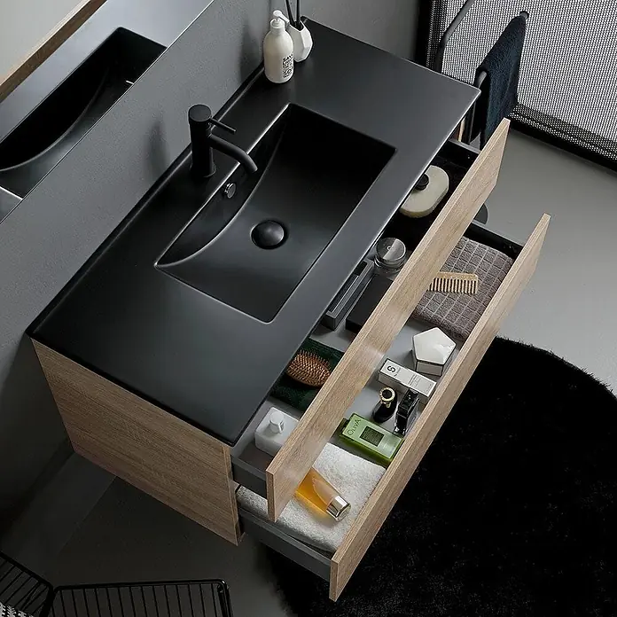 Kiamami Valentina Badmöbel-Set - Braun - Moderner Badunterschrank mit schwarzem integriertem Waschbecken und zwei offenen hellen Holzschubladen mit Toilettenartikeln.