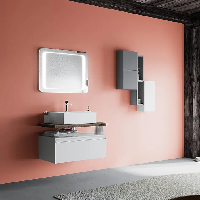 Kiamami Valentina Badmöbel-Set - Weiß - Moderne Badezimmereinheit mit weißem Waschbecken, Holzablage, hellgrauem Schrank, beleuchtetem Spiegel und zweifarbigen Wandschränken vor einer Korallenwand.