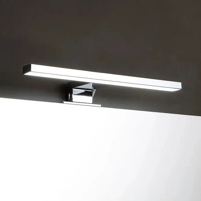 Kiamami Valentina Badmöbel-Set - Helles Holz - Elegante rechteckige LED-Spiegelleuchte in Chromoptik, strahlt helles weißes Licht aus, horizontal über einem Spiegel montiert.