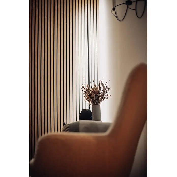 Ledvance Smart+ WiFi LED-Wandleuchte Floor Corner - L x B x H: 142 x 11 x 72 cm, Aluminum, Kaltweiß - Ein Trockenblumenarrangement in einer grauen Vase auf einer Oberfläche vor einer Holzlamellenwand.