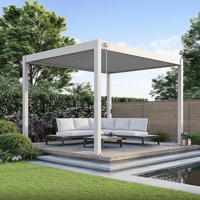 Weide Pergola Classic 3 x 3,6 M Ivory Sand - Farbe Gestell: Sand, Aluminium - Weiße Lamellenpergola über Outdoor-Sitzgruppe auf einer Holzterrasse im Garten neben einem Teich.