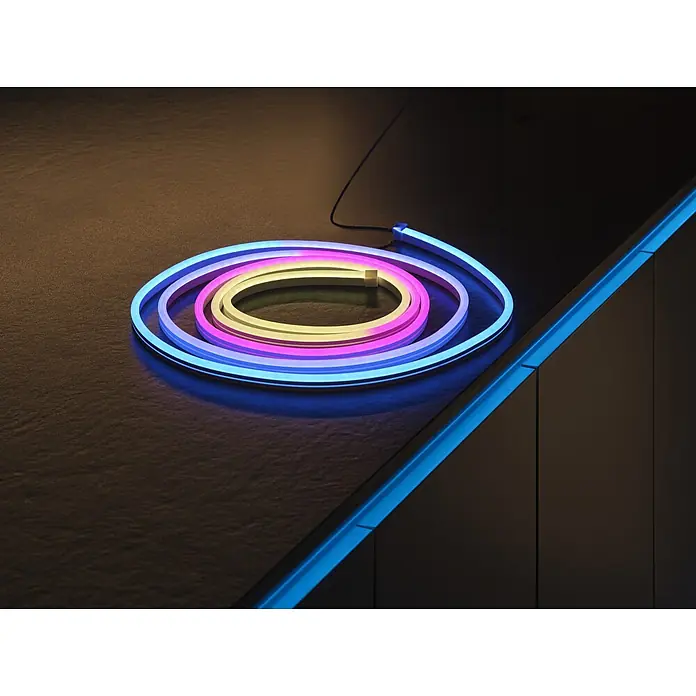 Osram Smart+ LED-Band Flex - Länge: 300 cm, Lichtfarbe: RGBW, 14 W, 1.500 lm, 220 V - 240 V - Mehrfarbige spiralförmige Neon-LED-Lichtleiste auf dunkler, strukturierter Oberfläche, die Umgebungslicht abgibt.