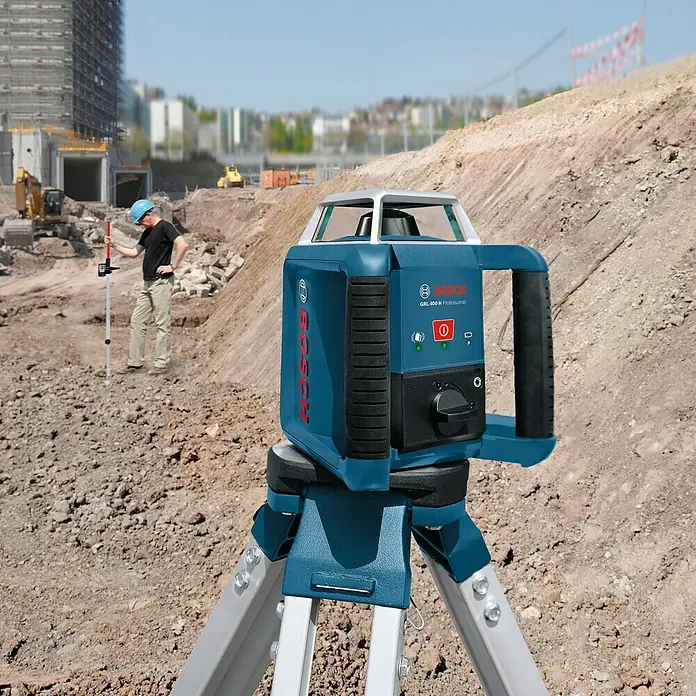 Bosch Professional Rotationslaser GRL 400 H - Max. Arbeitsbereich: 20 m, 8 -tlg. - Bosch GRL 400 H Professional Rotationslaser auf einem Stativ auf einer Baustelle, mit einem Bauarbeiter im Hintergrund.