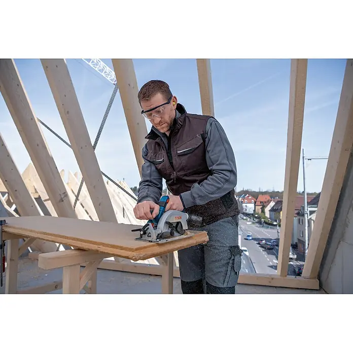 Bosch Professional AMPShare 18V Akku-Handkreissäge GKS 18V-57-2 L - 18 V, Ohne Akku, Durchmesser Sägeblatt: 165 mm, 5.000 U/min - Mann nutzt blaue und graue Bosch Handkreissäge zum Sägen eines Holzbretts.