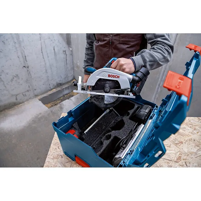 Bosch Professional AMPShare 18V Akku-Handkreissäge GKS 18V-57-2 L - 18 V, Ohne Akku, Durchmesser Sägeblatt: 165 mm, 5.000 U/min - Person legt eine silberne und blaue Bosch Akku-Kreissäge mit schwarzem Sägeblatt in einen blauen Werkzeugkoffer.