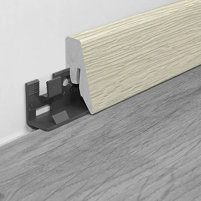 LOGOCLIC Sockelleiste K40 C Eiche Sarno - 260 cm x 19 mm x 40 mm, MDF - Holzfarbene Sockelleiste mit grauer Halterung auf grauem Bodenbelag. Ideal für saubere Übergänge und einfache Montage.
