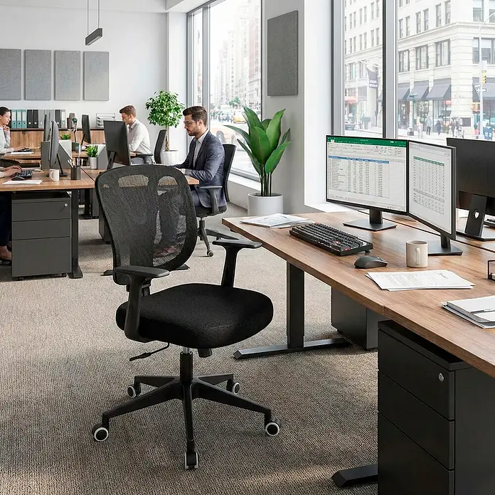 Silla de oficina Ana - Negro, Reposabrazos - Silla de oficina de malla negra en un entorno de oficina moderna de planta abierta, situada en un escritorio de madera con monitores dobles.