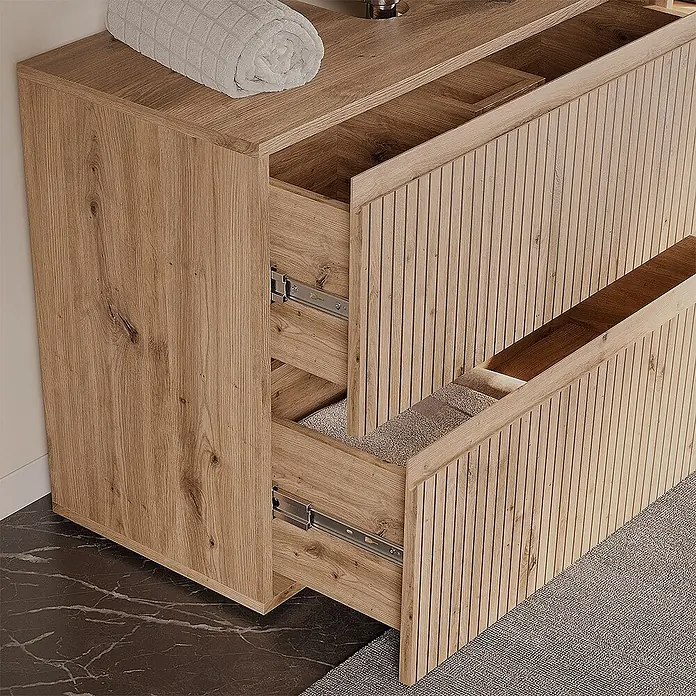 Vicco Badmöbel-Set Takumi Artisan 2 Teile - Artisan-Eiche, Matt - Heller Waschtischunterschrank mit geriffelten Schubladenfronten. Zwei teilweise geöffnete Schubladen zeigen Stauraum, mit einem gerollten Handtuch darauf.