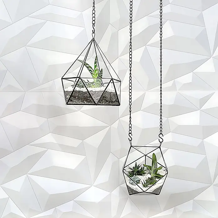 Profhome Wandpaneel 3D 705475 Glacier Matte White Dekorpaneel abstraktes Muster weiß 2 m2 - 610 x 600 mm - Zwei hängende geometrische Glasterrarien mit schwarzen Metallrahmen und Ketten, gefüllt mit Sukkulenten und weißem Kies.