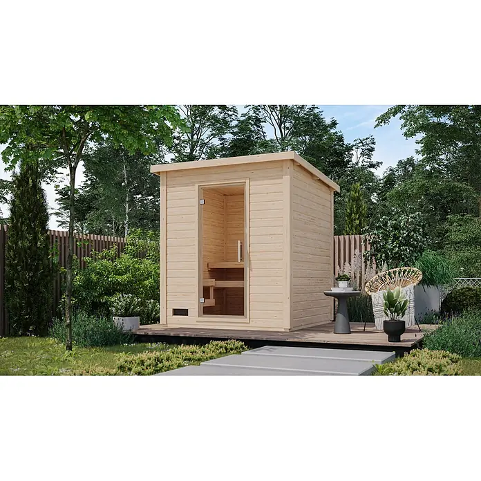 Karibu Saunahaus Kaapi 3 - 9 KW Bio-Ofen mit externer Steuerung, Natur, L x B x H: 196 x 196 x 228 cm - Hellholz-Außensauna mit Glastür, auf einer dunklen Holzterrasse in einem üppigen Garten.