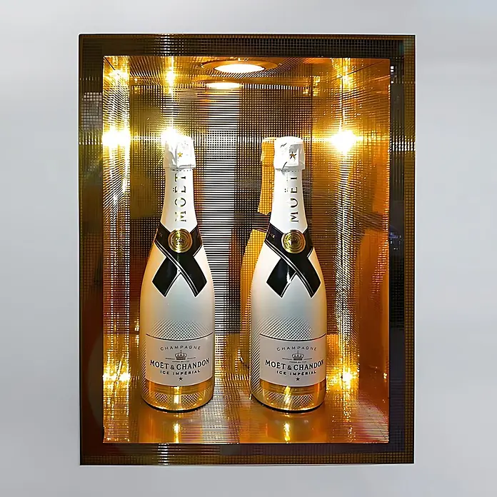 Wallface Wandpaneel 27373 M-Style Design Platte Wand-paneel Mosaik Dekor glanz gold 0,96 qm - 980 x 980 mm - Zwei weiße Moët & Chandon Ice Impérial Champagnerflaschen mit Gold- und Schwarzakzenten, in einer beleuchteten Goldnische präsentiert.