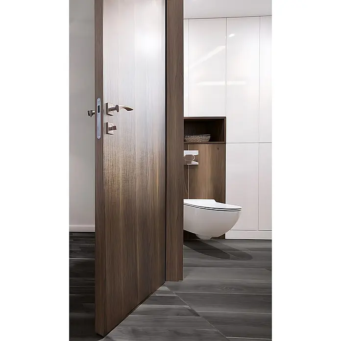 Wallface Wandpaneel 25159 NUTWOOD Wandpaneel Holz Optik Nussbau Dekor dunkelbraun 2,60 qm - dunkel-braun, 2.600 x 1.000 mm - Moderne Holztür mit markanter strukturierter Platte und Metallgriffen, öffnet sich zu einem eleganten Badezimmer mit Wand-WC.