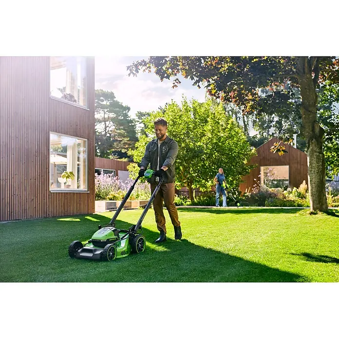 Greenworks Akku-Rasenmäher Gen2 GW 2X24V BL 46 cm - 48 V, 2 Akkus, 4 Ah, Schnittbreite: 33 mm - Mann mäht grünen Rasen mit einem grünen Greenworks Rasenmäher.