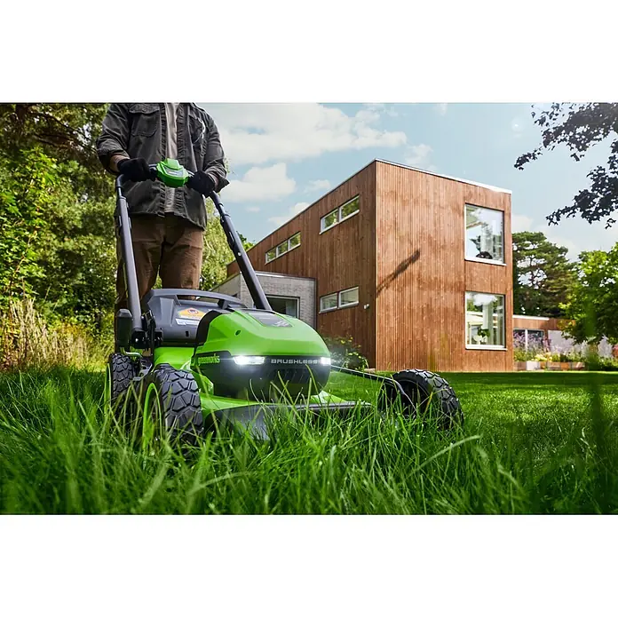 Greenworks Akku-Rasenmäher Gen2 GW 2X24V BL 46 cm - 48 V, 2 Akkus, 4 Ah, Schnittbreite: 33 mm - Grün-schwarzer Rasenmäher mit Scheinwerfern, von einer Person beim Mähen im Garten bedient.