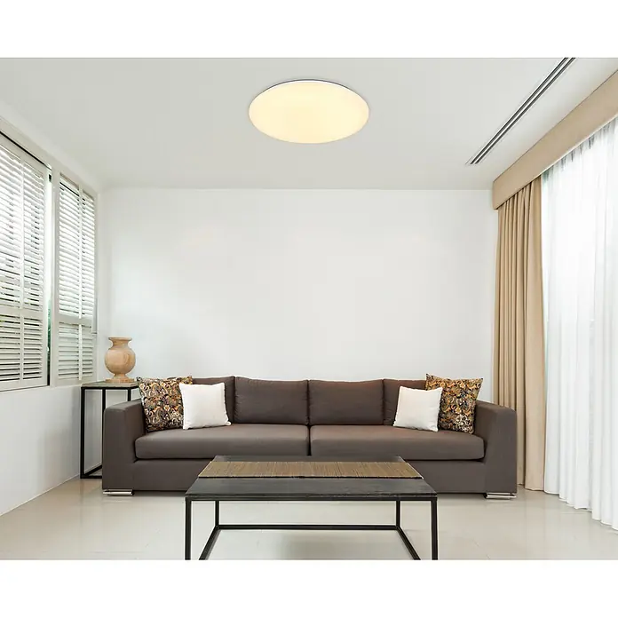 Globo LED-Deckenleuchte rund Eclypse - 24 W, Ø x H: 10 x 9 cm, Weiß Opal - Helles, modernes Wohnzimmer mit dunklem Stoffsofa, Zierkissen, dunklem Couchtisch und runder Deckenleuchte.
