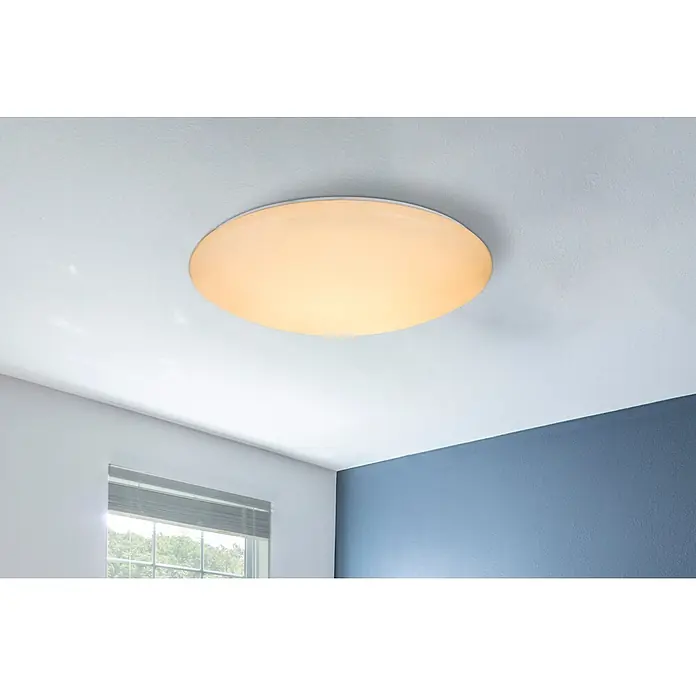 Globo LED-Deckenleuchte Atreju - 48 W, Weiß, RGB - Runde, beleuchtete Deckenleuchte mit warmem, gesprenkeltem Lichtschein an einer Decke in einem modernen Raum.