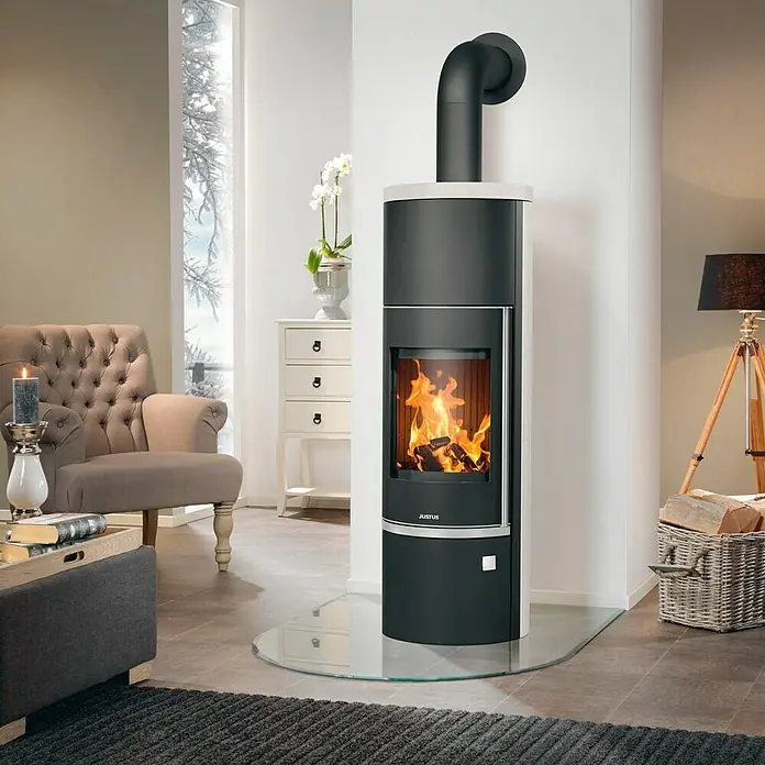 Justus Kaminofen Faro Aqua 2.0 - 8,5 kW, Raumheizvermögen: 200 m³, Material Verkleidung: Speckstein, Gussgrau/Speckstein - Elegantes Wohnzimmer mit einem stilvollen Justus Kaminofen, der Wärme und Behaglichkeit ausstrahlt, ergänzt durch eine klassische Einrichtung.