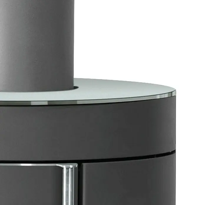 Justus Kaminofen Mino 2.0 - 5,5 kW, Raumheizvermögen: 88 m³, Farbe Verkleidung: Glas, Schwarz - Nahaufnahme eines modernen Kaminofens mit grauem Korpus und einer runden Glasplatte, die ein elegantes Designelement darstellt.