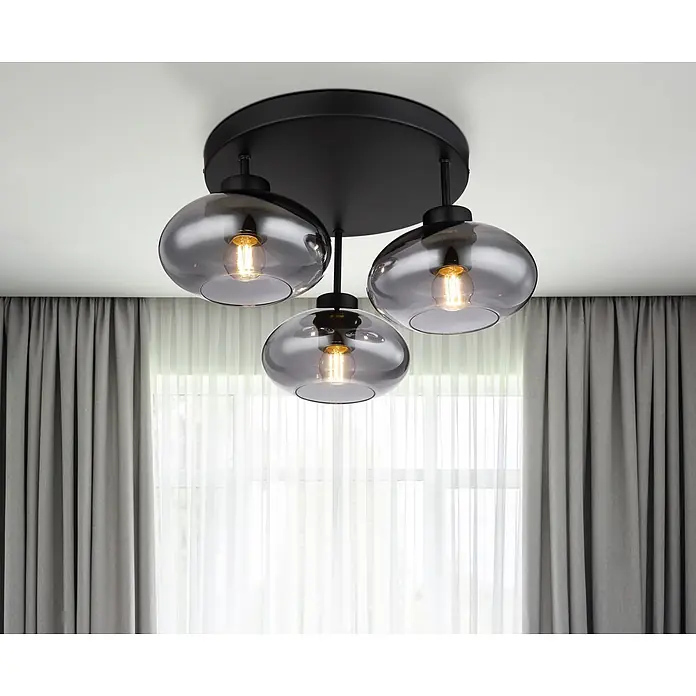 Globo Deckenleuchte Shaun - 40 W, E27 - Schwarze Deckenleuchte mit drei rauchgrauen Glasschirmen und Glühbirnen, hängt in einem Raum mit Fenster und grauen Vorhängen.