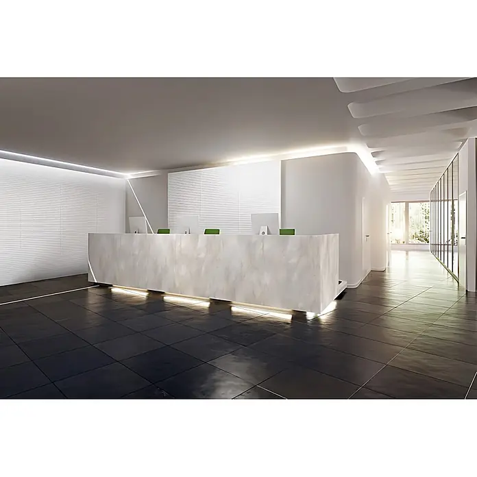 Wallface Wandpaneel 24954 RATTAN 20 Snow White Wandverkleidung 3D matt weiß 2,6 m2 - 2.600 x 1.000 mm - Moderner Empfangstresen aus hellem Marmor mit Unterbeleuchtung, Monitoren und grünen Stühlen in einer eleganten Bürolobby.