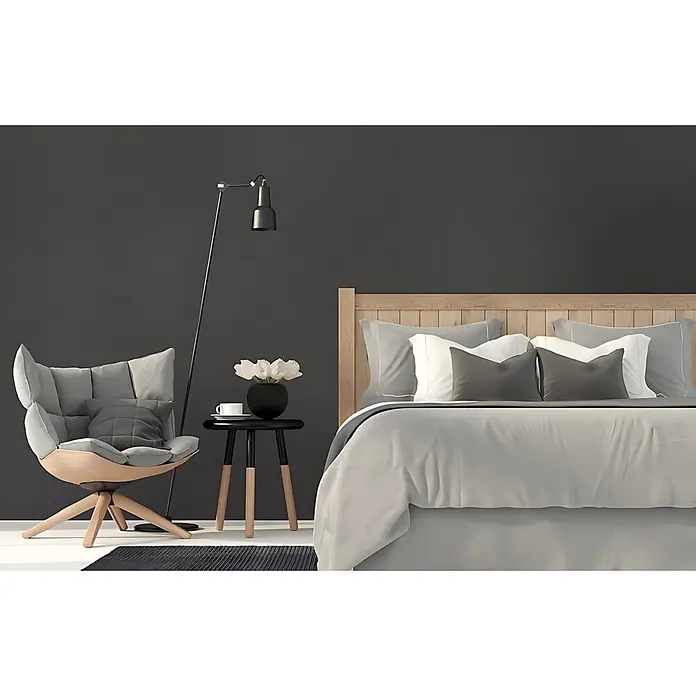 Wallface Wandpaneel 19762-NA Antigrav Charcoal Dark Wandpaneel Leder Optik anthrazit 2,6 m2 - 2.600 x 1.000 mm - Minimalistisches Schlafzimmer mit Holzbett, grauer und weißer Bettwäsche, hellem Holz-Sessel, schwarzem Beistelltisch und Stehlampe.