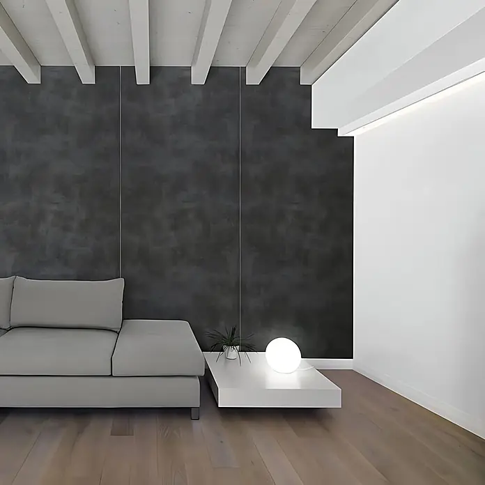 Wallface Wandpaneel 19092 CEMENT DARK Dekorpaneel in Beton Optik matt anthrazit 2,6 m2 - 2.600 x 1.000 mm - Modernes graues Modulsofa neben einem weißen rechteckigen Couchtisch mit einer leuchtenden Kugellampe in einem modernen Wohnraum.