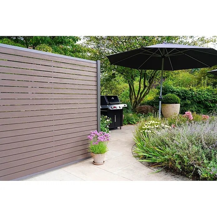 GartenLand Steckzaun-Element WPC Zaun Kopenhagen Ohne Pfosten - B x H: 180 x 180 cm, Schokobraun, Verbundwerkstoff - Braunes Verbundstoff-Lamellen-Gartenzaunelement mit grauem Rahmen, trennt Terrasse vom Garten.