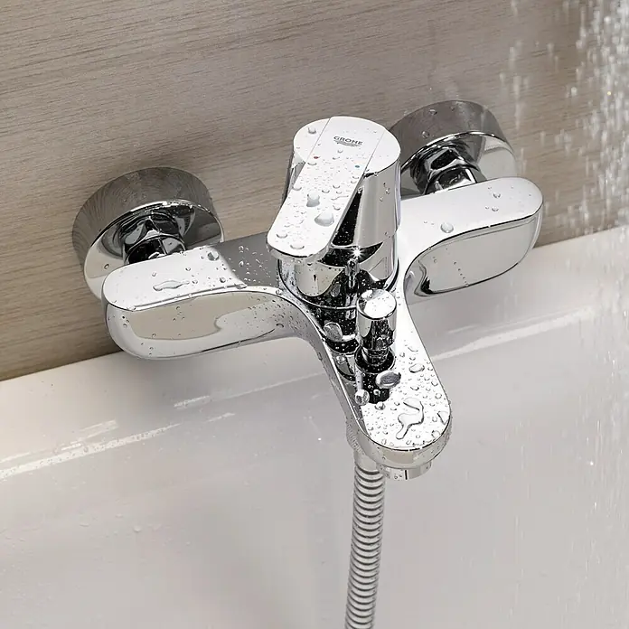 Grohe QuickFix Get Grifo monomando de bañera - Cromo, Brillante - Primer plano de un brillante grifo de bañera Grohe con manguera de ducha, cubierto de gotas de agua. Diseño de baño elegante con un acabado cromado moderno.