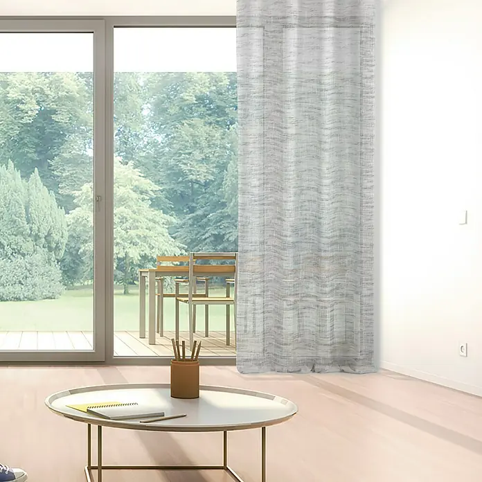 Visillo para ventana Argán - 140 x 250 cm, 100% poliéster, Gris - Vista de una sala de estar luminosa con una elegante cortina permeable a la luz que filtra suavemente la luz del día.