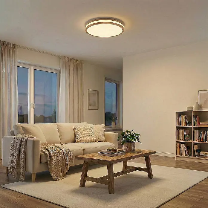 Lindby Deckenleuchte Emiva - Holz hell, Holz hell - Deckenleuchte mit rundem Holzrahmen und weißem Diffusor, beleuchtet ein Wohnzimmer.