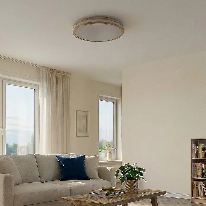 Lindby Deckenleuchte Emiva - Holz hell, Holz hell - Runde Deckenleuchte mit hellem Holzrahmen und weißem Diffusor, an einer hellen Decke in einem modernen Wohnzimmer montiert.