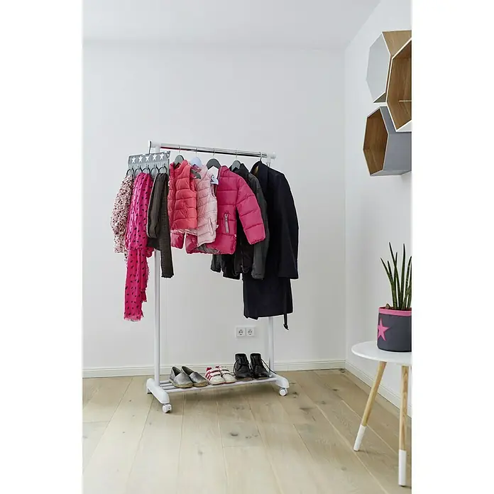 Store It Kleiderwagen - L x B: 44 x 84 cm, Höhenverstellung: 101 cm - 165 cm - Eine Garderobenstange mit Winterkleidung wie Jacken und Schals, sowie Schuhen. Eine Zimmerpflanze steht auf einem Beistelltisch.
