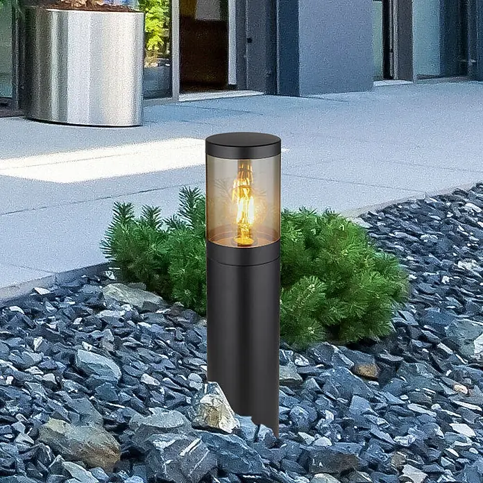Globo Außenstehleuchte Xeloo - Ø x H: 14 x 500 cm, Schwarz, E27 - Schwarze zylindrische Wegeleuchte mit amberfarbenem Glas und sichtbarer Edison-Birne, in grauem Kies neben einem Weg.