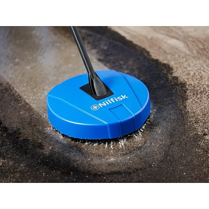 Nilfisk Hidrolimpiadora de alta presión CORE 125 Home - 125 bar, 1.400 W, Capacidad de bombeo: 438 l/h - Limpiador de patios Nilfisk azul limpiando activamente una superficie de hormigón sucia con salpicaduras de agua.