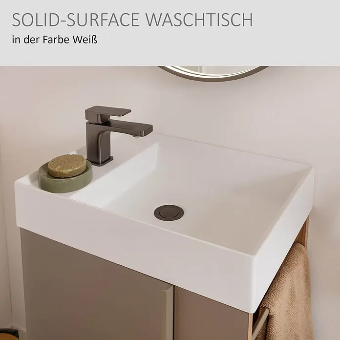 Camargue Marea Badmöbel-Set Mini - Gesamtbreite Badmöbel: 50 cm, Berg Eiche/Goldbronze, Matt - Weißer Solid-Surface Waschtisch mit dunklem Wasserhahn und Ablauf, auf einem braunen Waschtischunterschrank mit Handtuch.