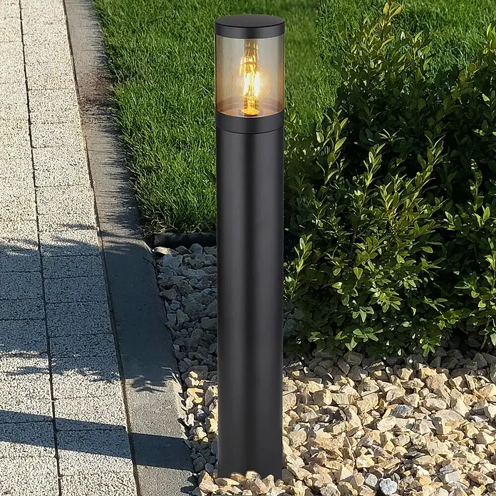 Globo Außenwegeleuchte Xeloo - Ø x H: 14 x 80 cm, E27, 60 W - Schwarze zylindrische Außenleuchte mit bernsteinfarbener Glühbirne, die einen Gartenweg beleuchtet.